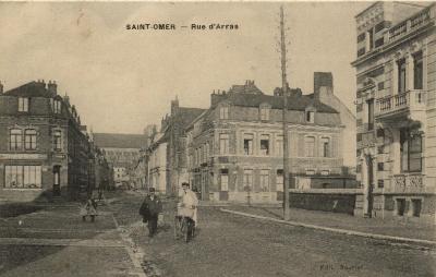 On se trouve au carrefour des rues de Thérouanne et Clémenceau, avec la rue d'Arras. On peut voir dans le fond les bâtiments du Lycée de St Omer.
